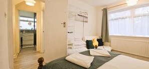 Habitació d'hotel amb un llit, una taula de nit, una finestra amb cortines i vista al bany.