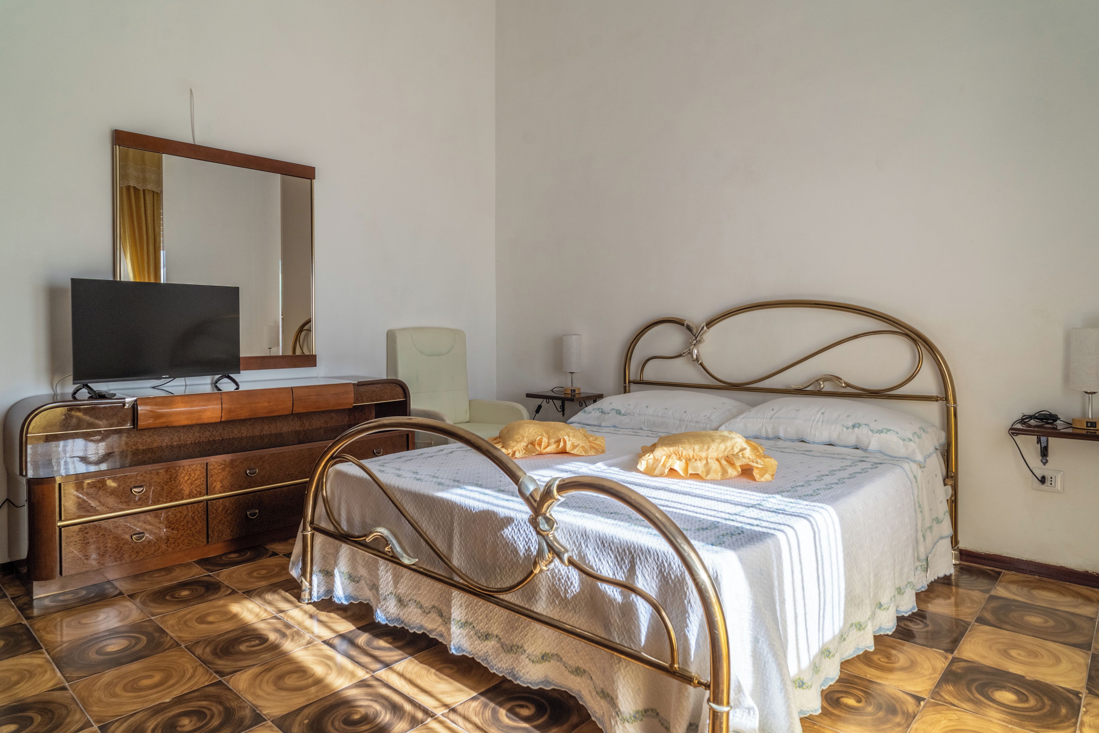 A bedroom with a bed, dresser, television, and a mirror.