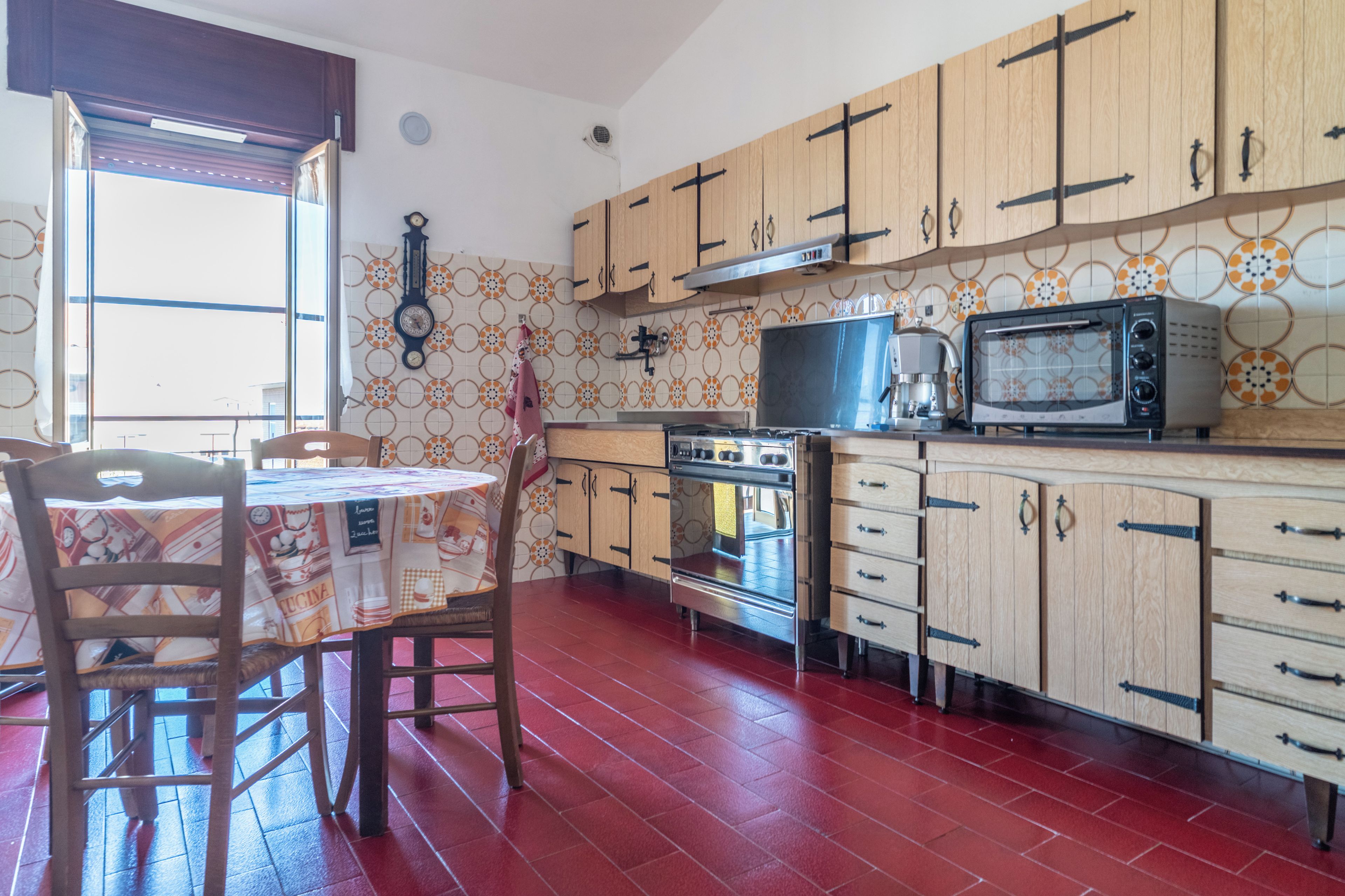 A kitchen with wooden cabinets, a stove, a microwave, and a dining table with chairs.