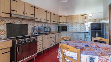 Una cocina con armarios de madera, una estufa, una cafetera y una mesa de comedor con sillas.