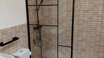 Un baño con cabina de ducha, inodoro y lavamanos.