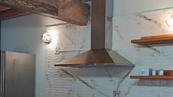 Una cocina con gabinetes de madera, una campana extractora de acero inoxidable y luces colgantes.