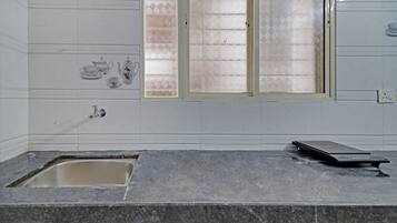 Un bagno con un piano d'appoggio in marmo, un lavandino, una finestra con vetro satinato e un piccolo riscaldatore elettrico a parete.