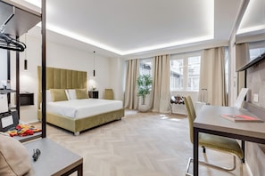 A hotel room with a bed, a desk, a chair, a potted plant, and a window with curtains. - Glam44 Private Suites (ROMA)