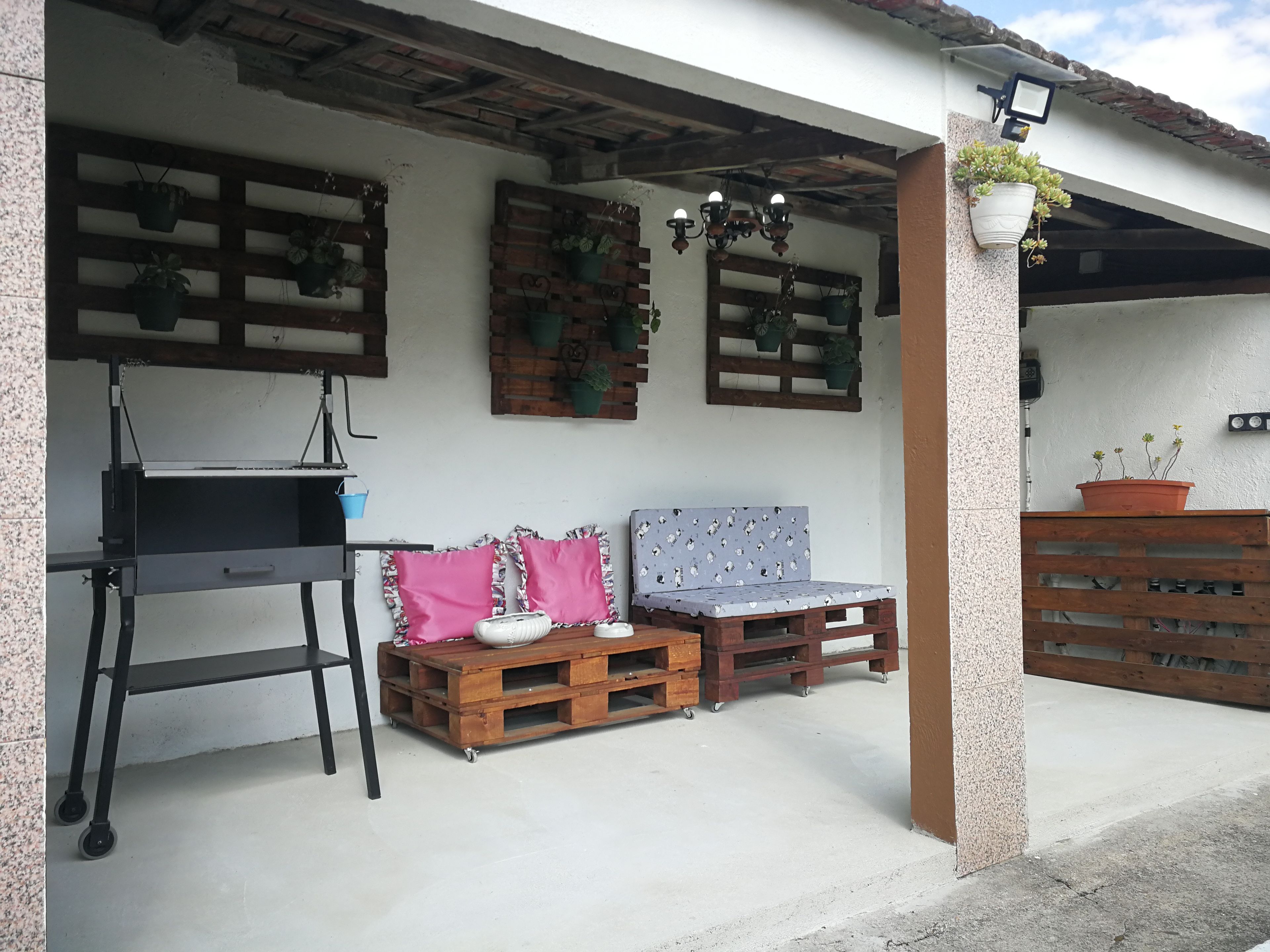 Eine Außenpatio mit Grill, Sitzgelegenheit und Topfpflanzen.