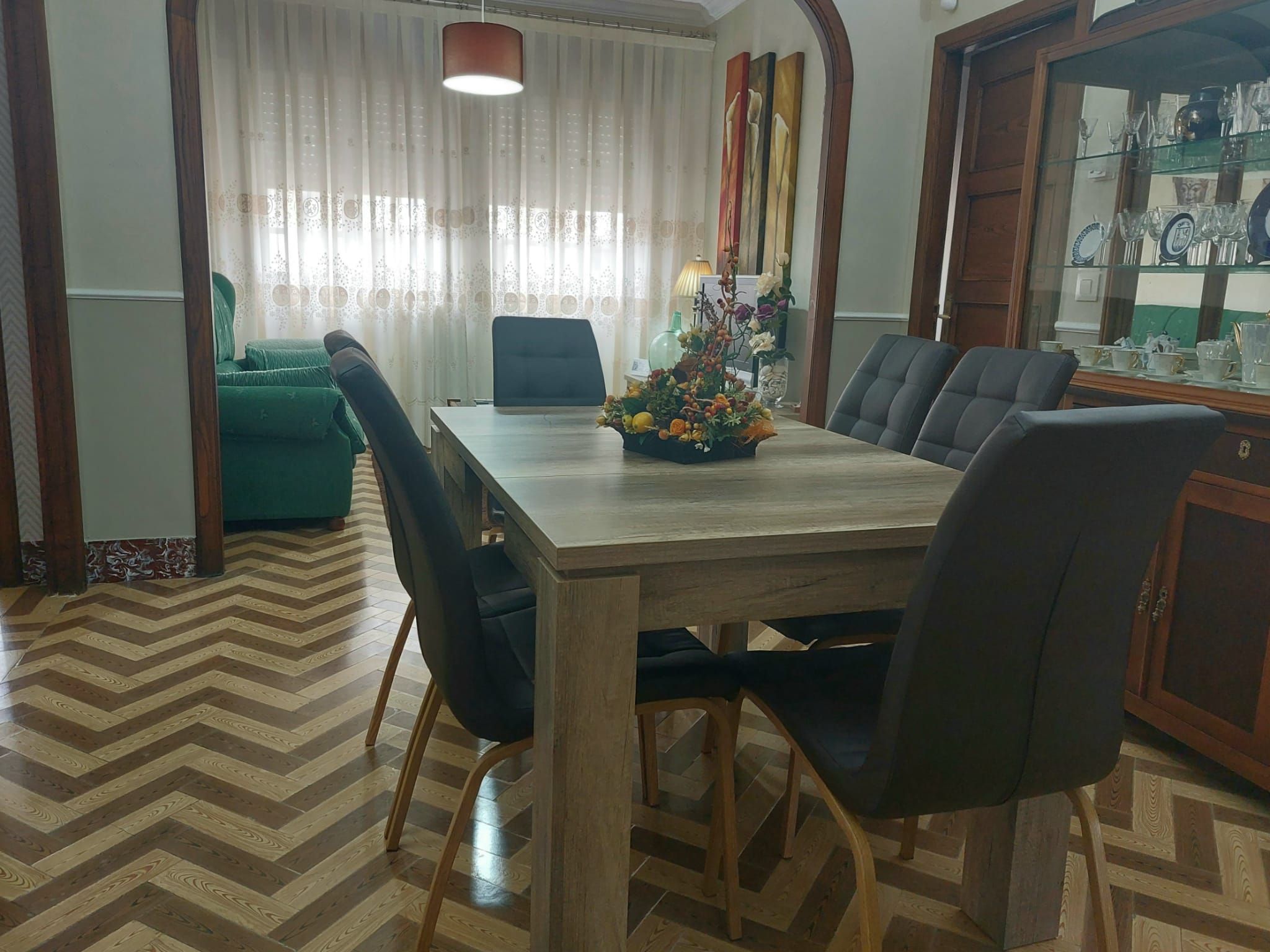 A dining area with a wooden table, black chairs, and a floral centerpiece.