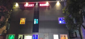 A building with a sign reading 'Galaxy Rooms' and multiple illuminated windows. - Hotel O by OYO Galaxy Hospitality (Pune)