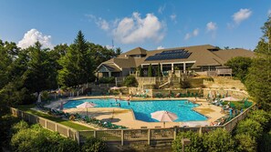 Ein Resort mit großzügigem Poolbereich, zahlreichen Liegestühlen und einer überdachten Terrasse.
