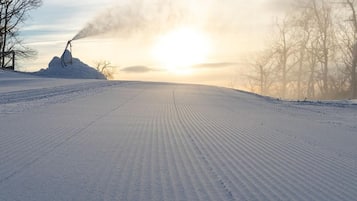 A snow-covered road with tire tracks and a distant snow mound.