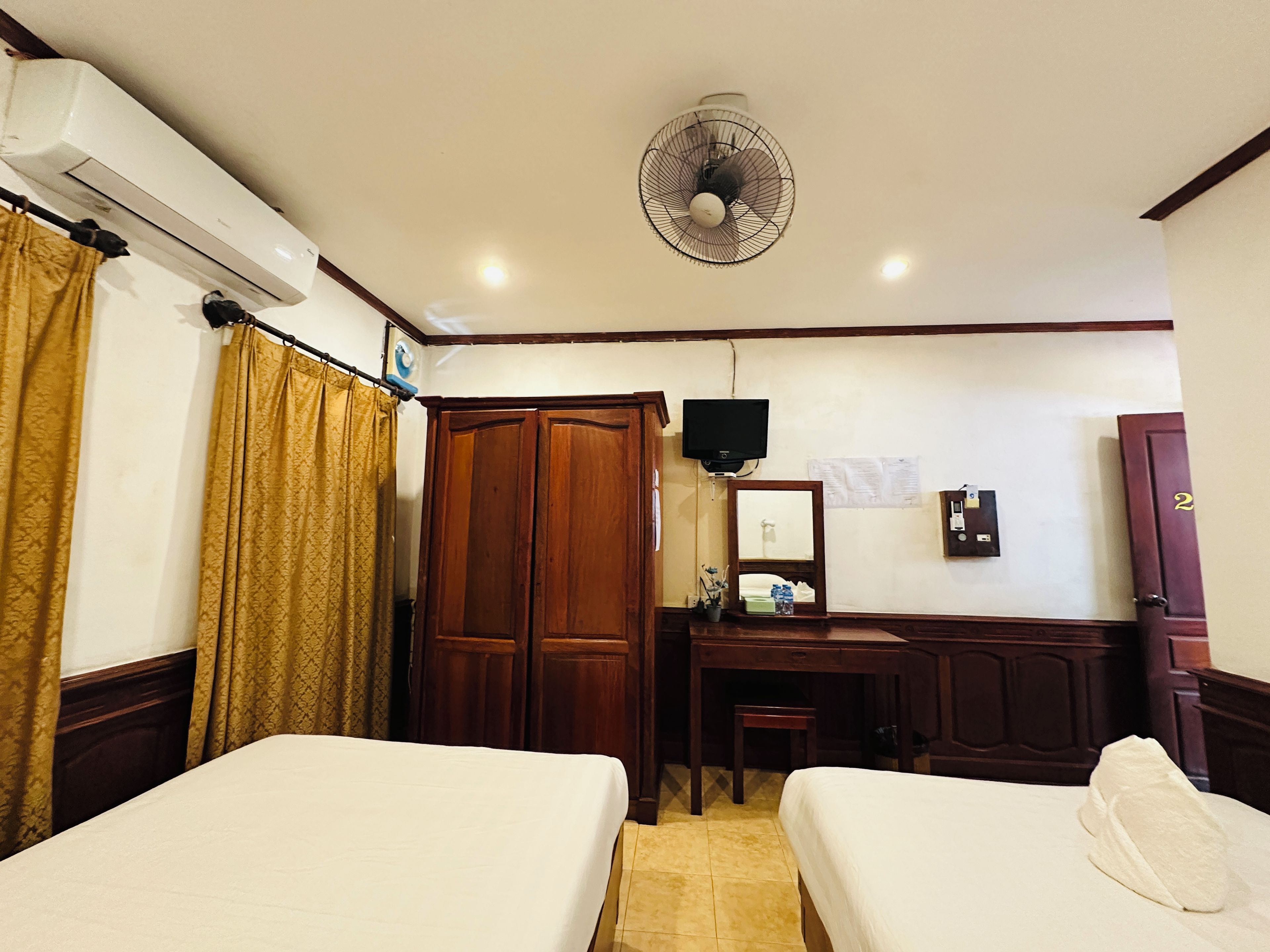 Habitación de hotel con dos camas, un escritorio, un espejo, un televisor y un armario.