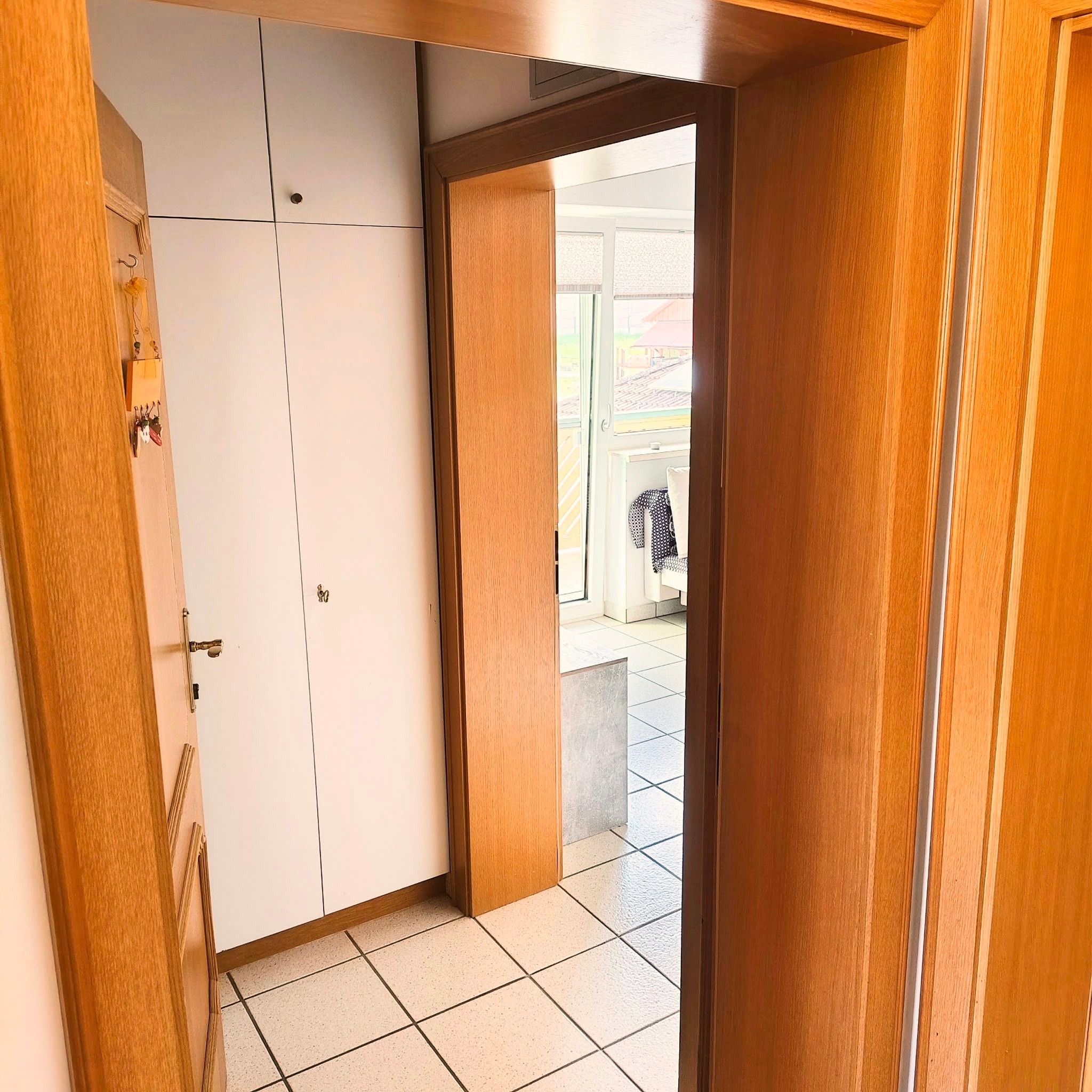 Een kamer met een inloopkast, een deur naar buiten en een betegelde vloer.