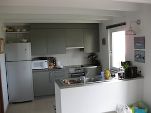 A kitchen with grey cabinets, a white refrigerator, a microwave, and a sink. - New Listing (Locmaria)