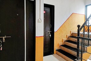 A staircase with black and yellow steps, a black door with a red number, and a metal handrail. - Hotel O Way Point (Pune)