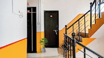A hallway with a staircase leading to a black door marked with the number 104.
