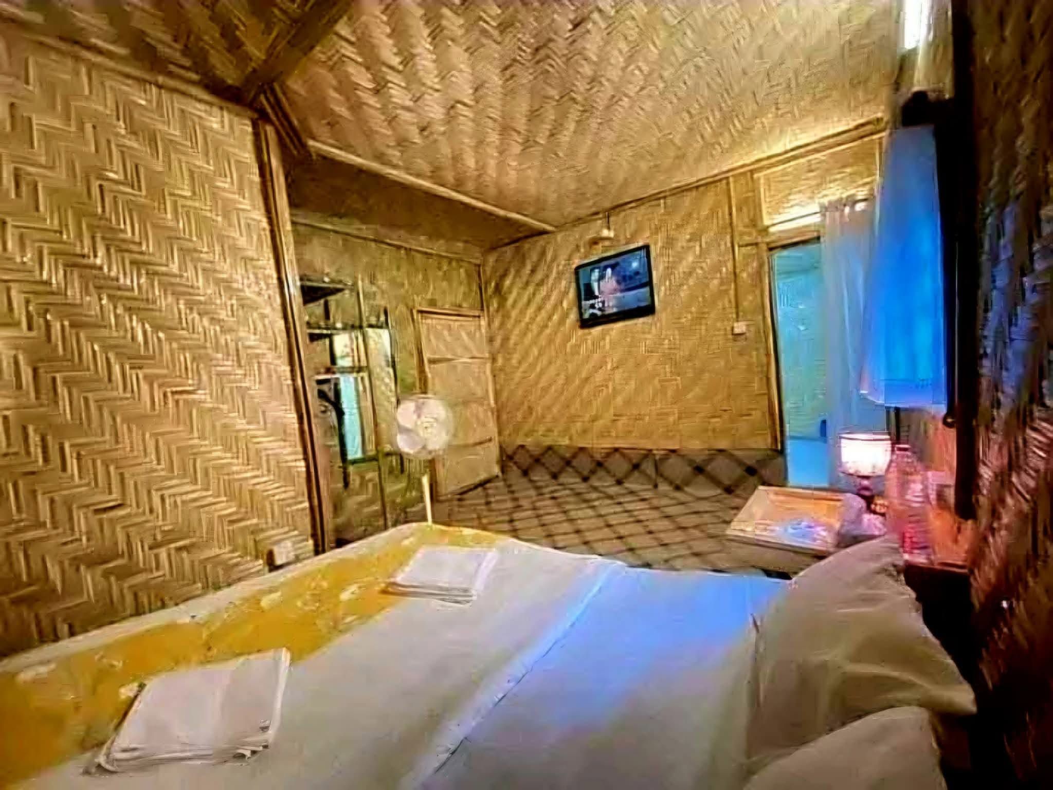 Ein Zimmer mit Schachbrettmuster-Boden, einem an der Wand befestigten Fernseher und einem Bett mit Kissen und Decke.