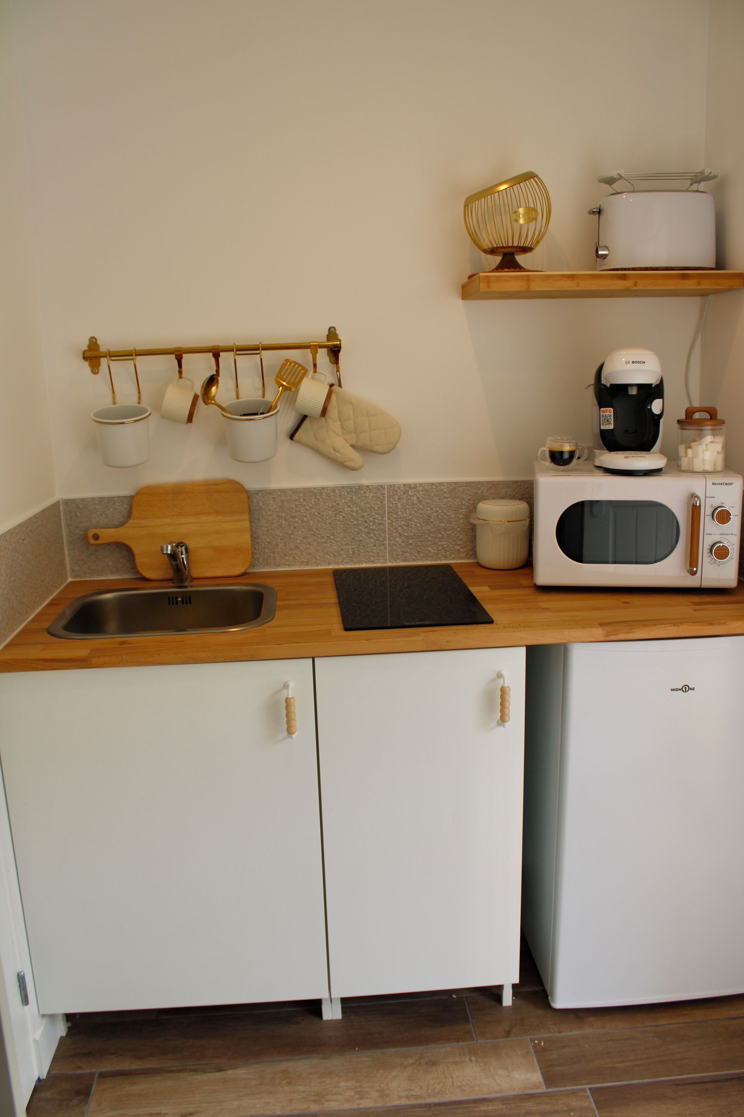 A kitchen with a wooden countertop, a sink, a microwave, and a coffee maker.