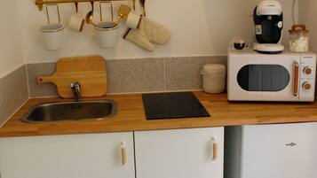 A kitchen with a wooden countertop, a sink, a microwave, and a coffee maker.