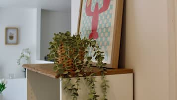 Une pièce dans laquelle on trouve une étagère fixée au mur, sur laquelle sont posés un tableau encadré et une plante en pot.