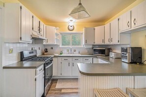 Una cocina moderna con armarios blancos, horno empotrado, microondas y un amplio ventanal.