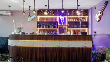 A bar area with a curved counter, shelves of bottles, and hanging pendant lights.