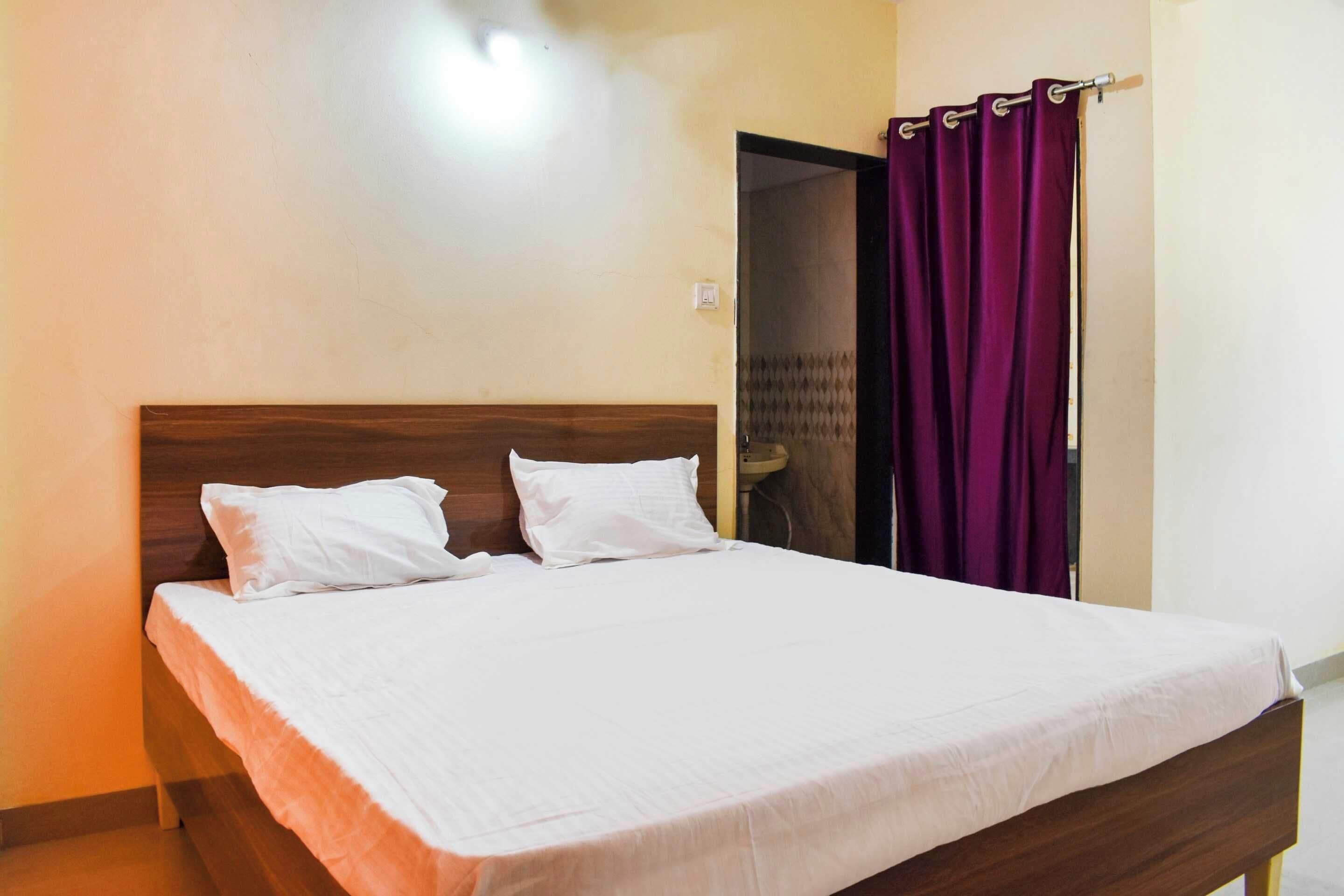 A single-bed room with a wooden headboard, white bedding, and a purple curtain.