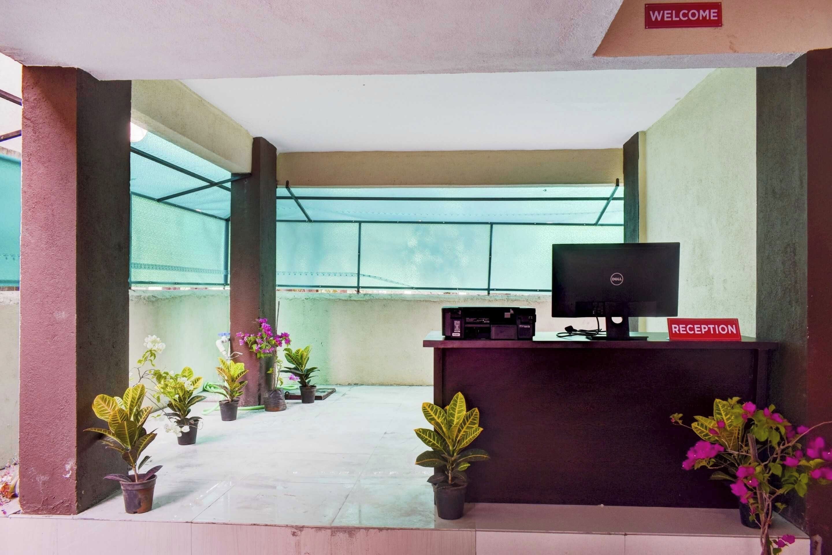 A reception area with a reception desk, a television, and potted plants.