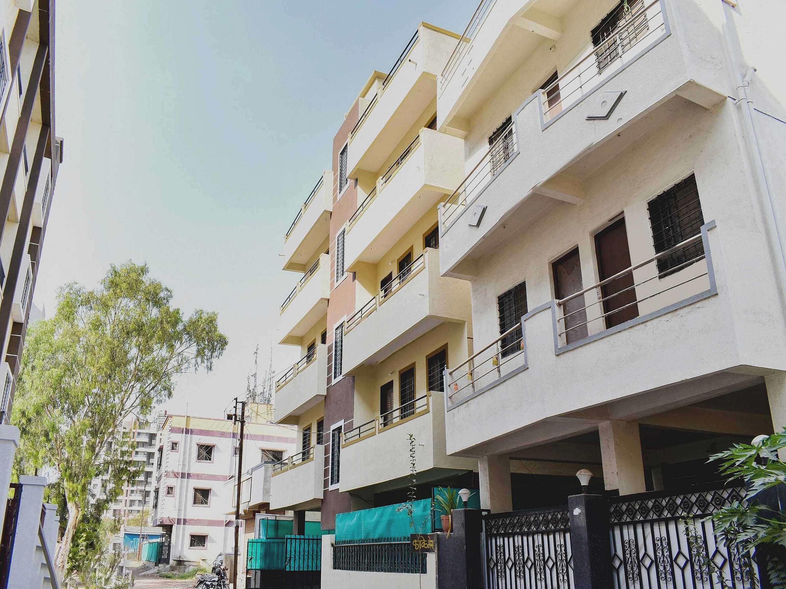 A multi-story residential building with balconies, a gated entrance, and a clear sky.