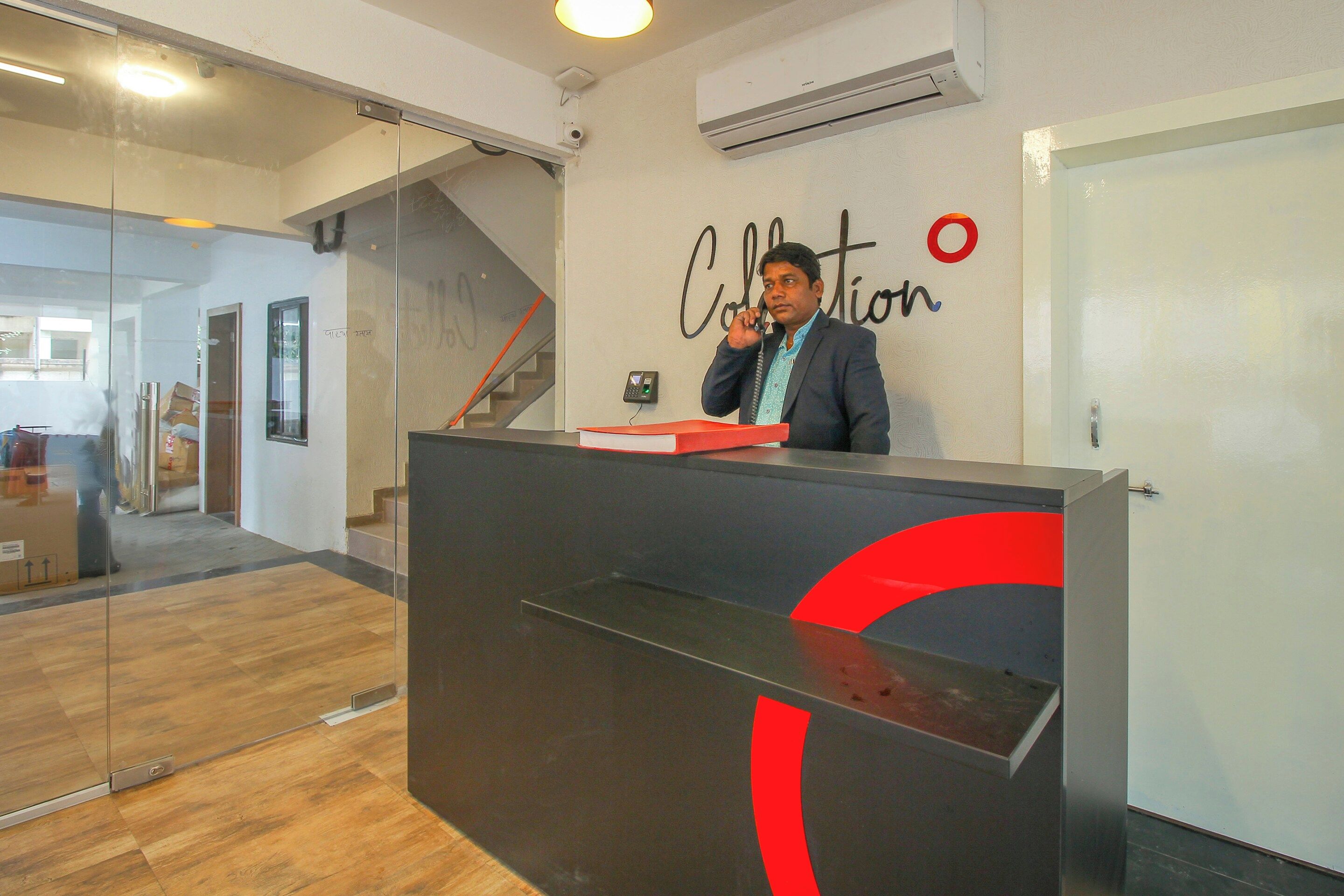 A reception desk with a glass partition, a staircase, and a wall-mounted air conditioning unit.