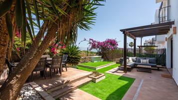 A patio with outdoor furniture, a pergola, and a view of the sea.