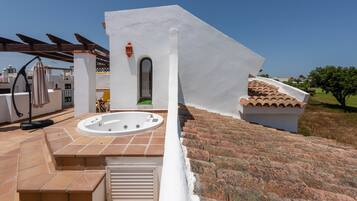 Une terrasse sur le toit dotée d’un jacuzzi, d’une pergola et offrant une vue sur le paysage environnant.