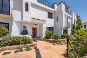 Un bâtiment blanc doté de nombreux balcons, d’un chemin pavé et de jardins bien entretenus.