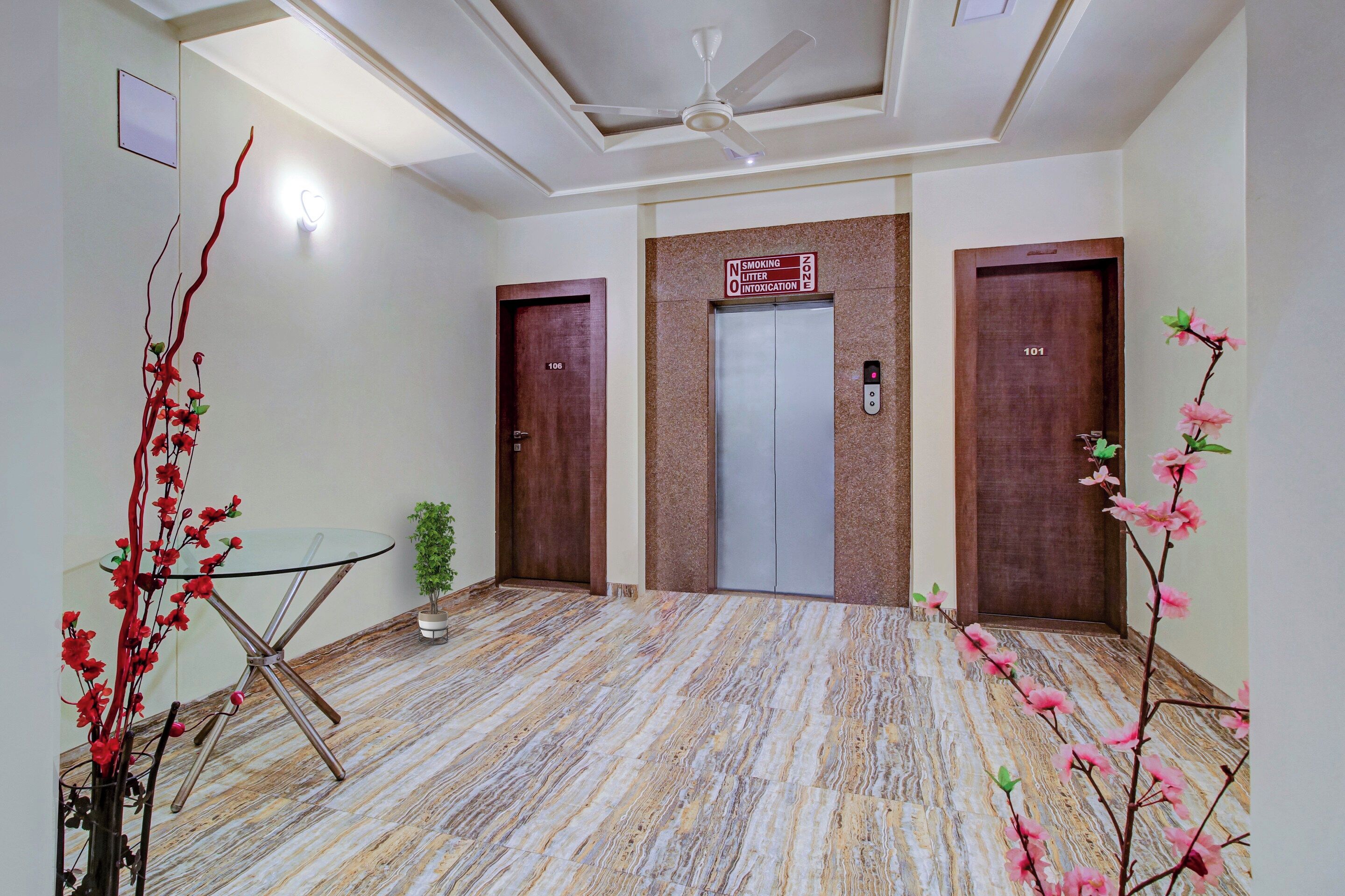 Un hall d’hôtel avec un sol en marbre, un ventilateur de plafond et trois portes en bois.