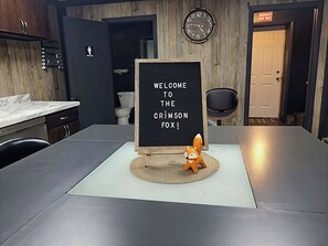 Eine moderne Küche mit einer Marmorarbeitsplatte, einer Uhr und einem Willkommensschild mit einem Fuchs.