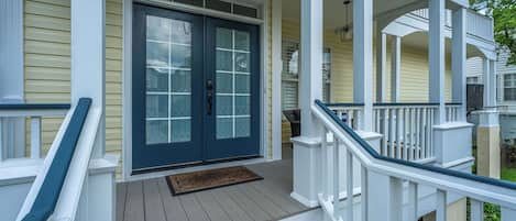A porch with a double door, a small step leading up to it, and a doormat.