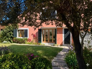Una casa con jardín, un camino pavimentado y un árbol en primer plano.