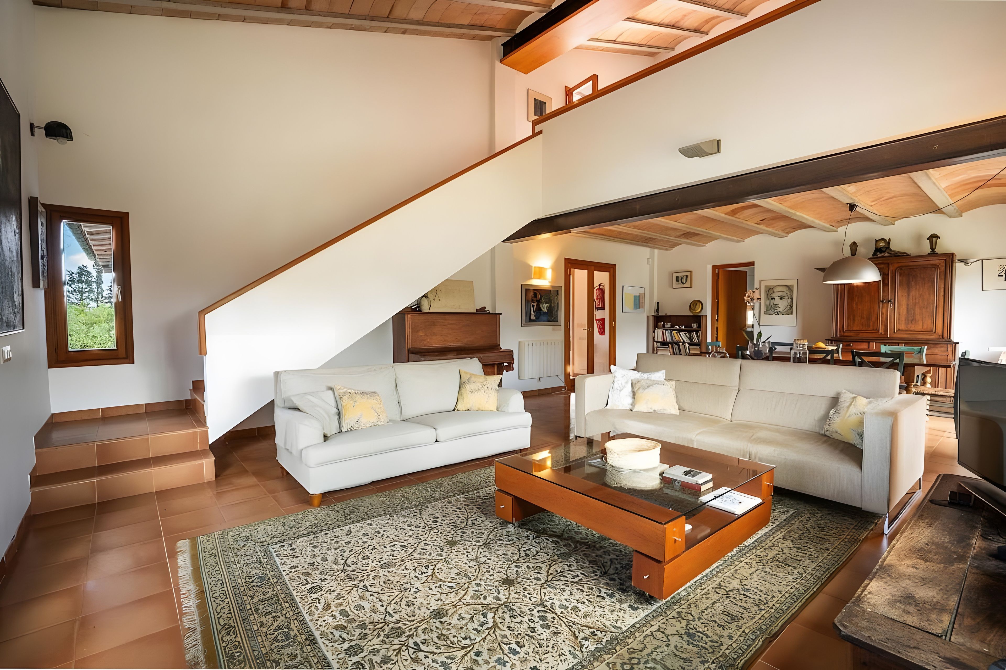 A spacious living area with two sofas, a coffee table, and a staircase leading to an upper level.