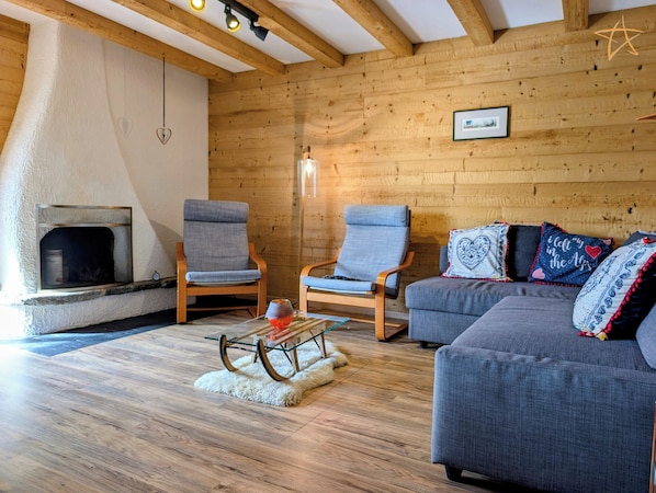 Un salon chaleureux avec une cheminée, deux fauteuils, un canapé et une table basse.