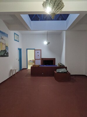 A room with a sloped ceiling, a bed, a small table, and a wall-mounted heater.