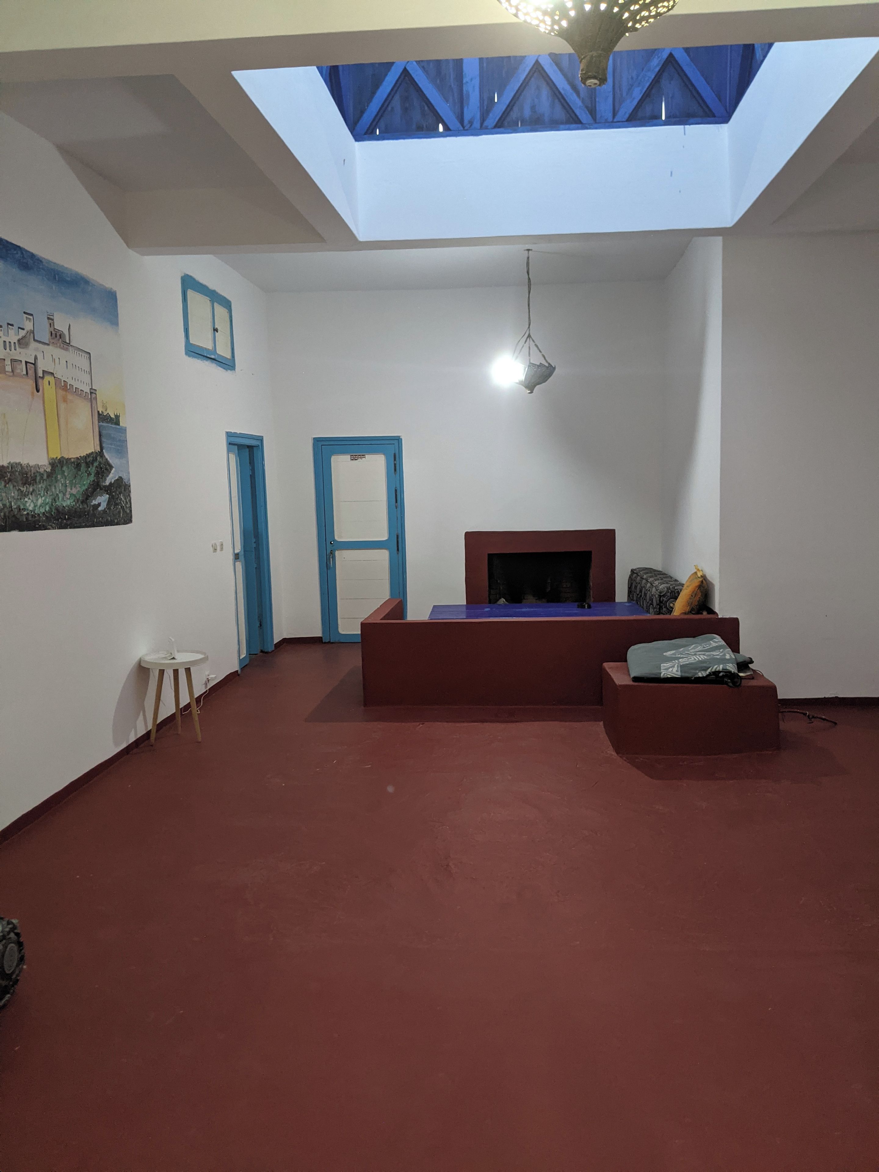 Una habitación con techo inclinado, una cama, una mesita y una puerta.