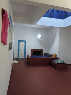 A room with a bed, a desk, a chair, a hanging light fixture, and a door.