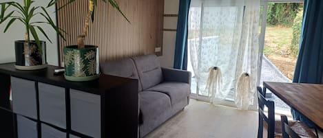 A living room with a sofa, a wooden table, and two potted plants.
