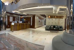 A hotel lobby with a reception desk, seating area, and a marble floor. - mawasem al khair hotel (makkah)