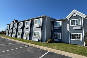 A multi-story building with a parking lot in front. - Coratel Plus Suites By Jasper Faribault (Faribault)