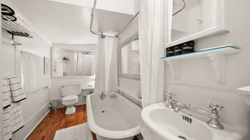 Une salle de bain avec une baignoire, deux lavabos, des toilettes et un miroir.