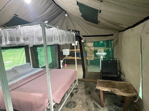 A tent with a bed, a small table, and a sink.