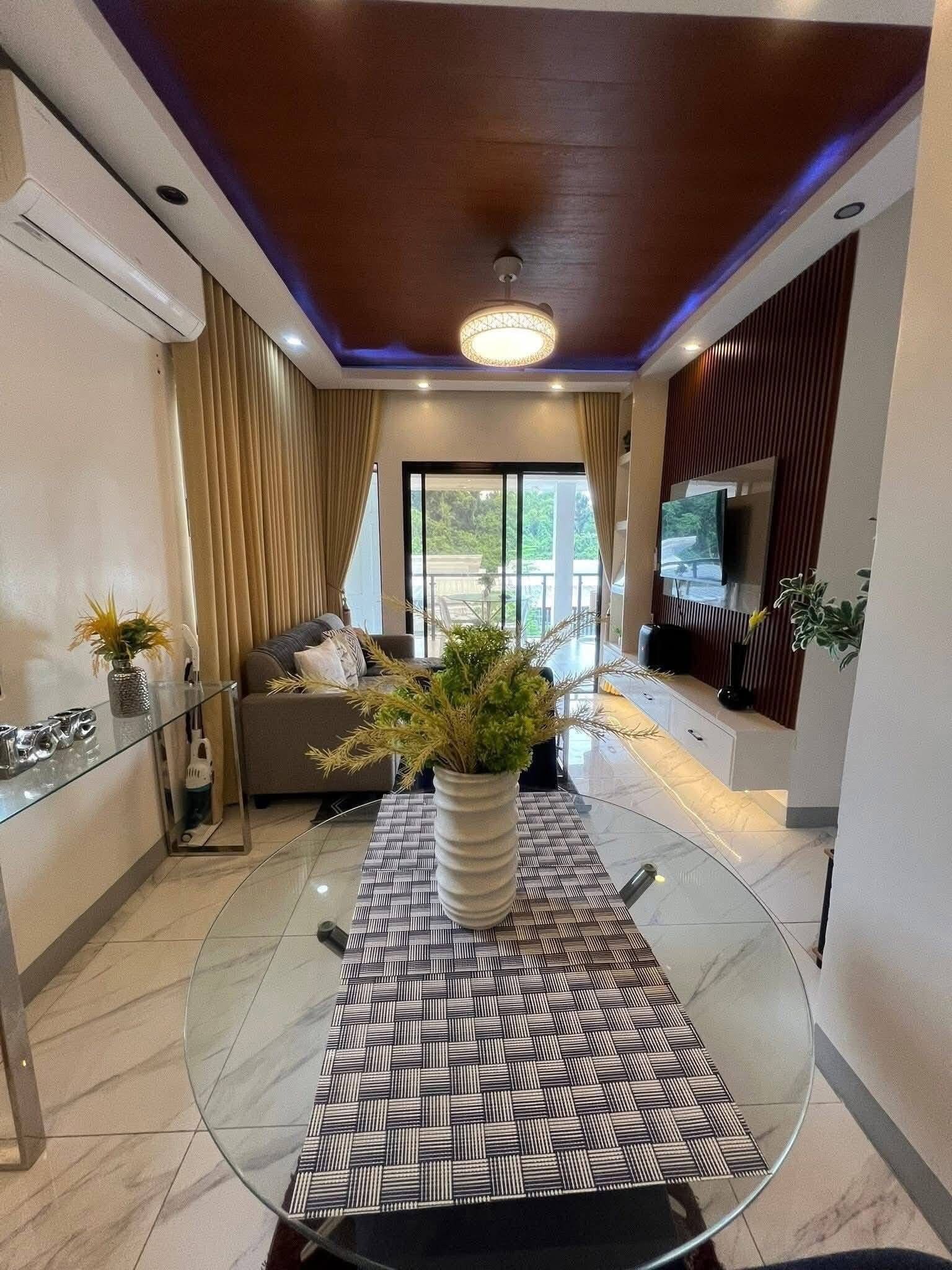 Una sala de estar moderna con una mesa de comedor de vidrio, un sofá y un televisor.