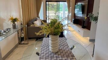 Una sala de estar moderna con una mesa de comedor de vidrio, un sofá y un televisor.
