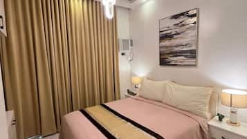 Habitación de hotel con cama, mesitas de noche, lámpara, un cuadro y una lámpara en el techo.