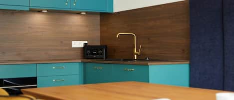 Cozinha moderna com armários verde-água, bancada de madeira e um rádio preto.