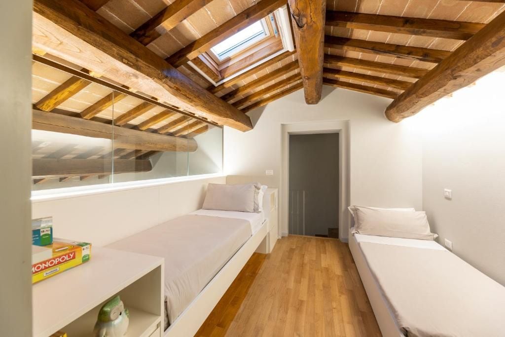 A small, compact room with two beds, a skylight, and a wooden ceiling.